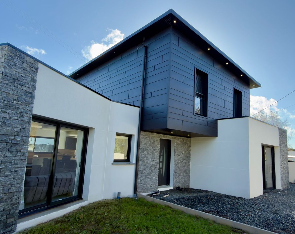 Maison contemporaine dont l'étage est habillé d'aluminium anthracite à joints décalés, sur un rez-de-chaussée en pierre et enduit clair