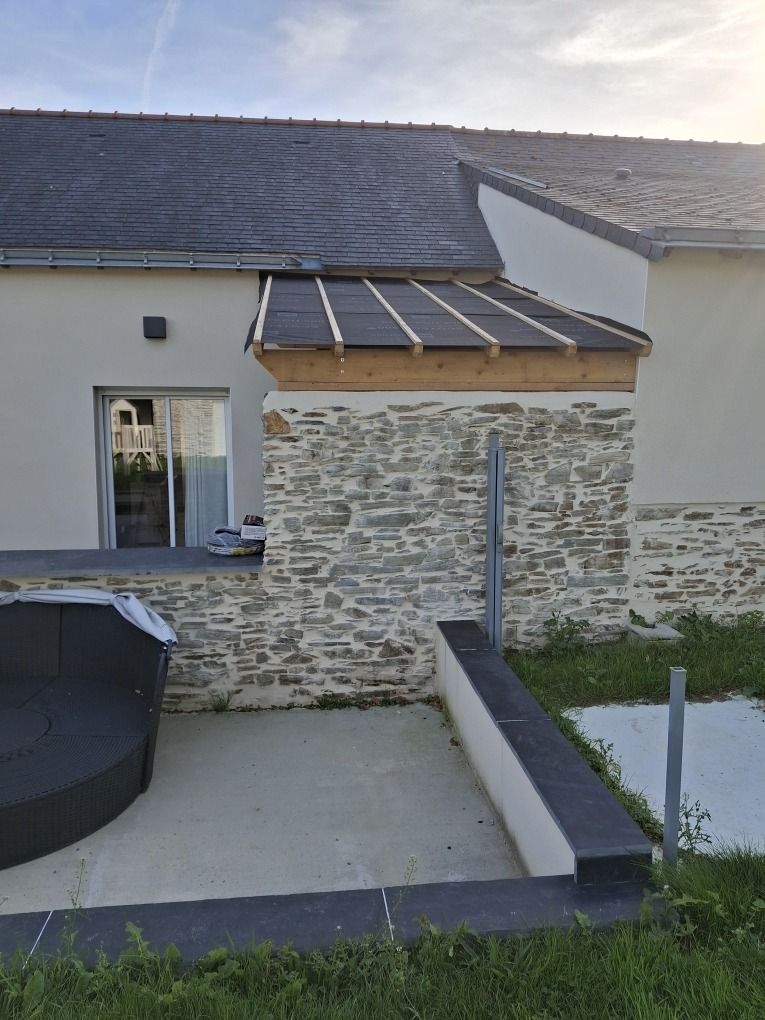 Toiture d'un four à pain en cours de rénovation : charpente neuve, écran de sous-toiture et contre-lattage posés sur un mur en pierre
