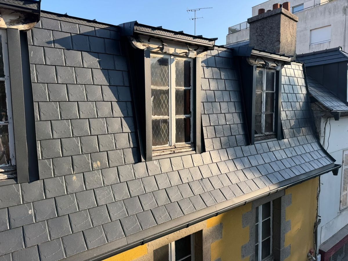 Toiture en ardoise usée et lucarnes anciennes sur une façade jaune, avant réfection